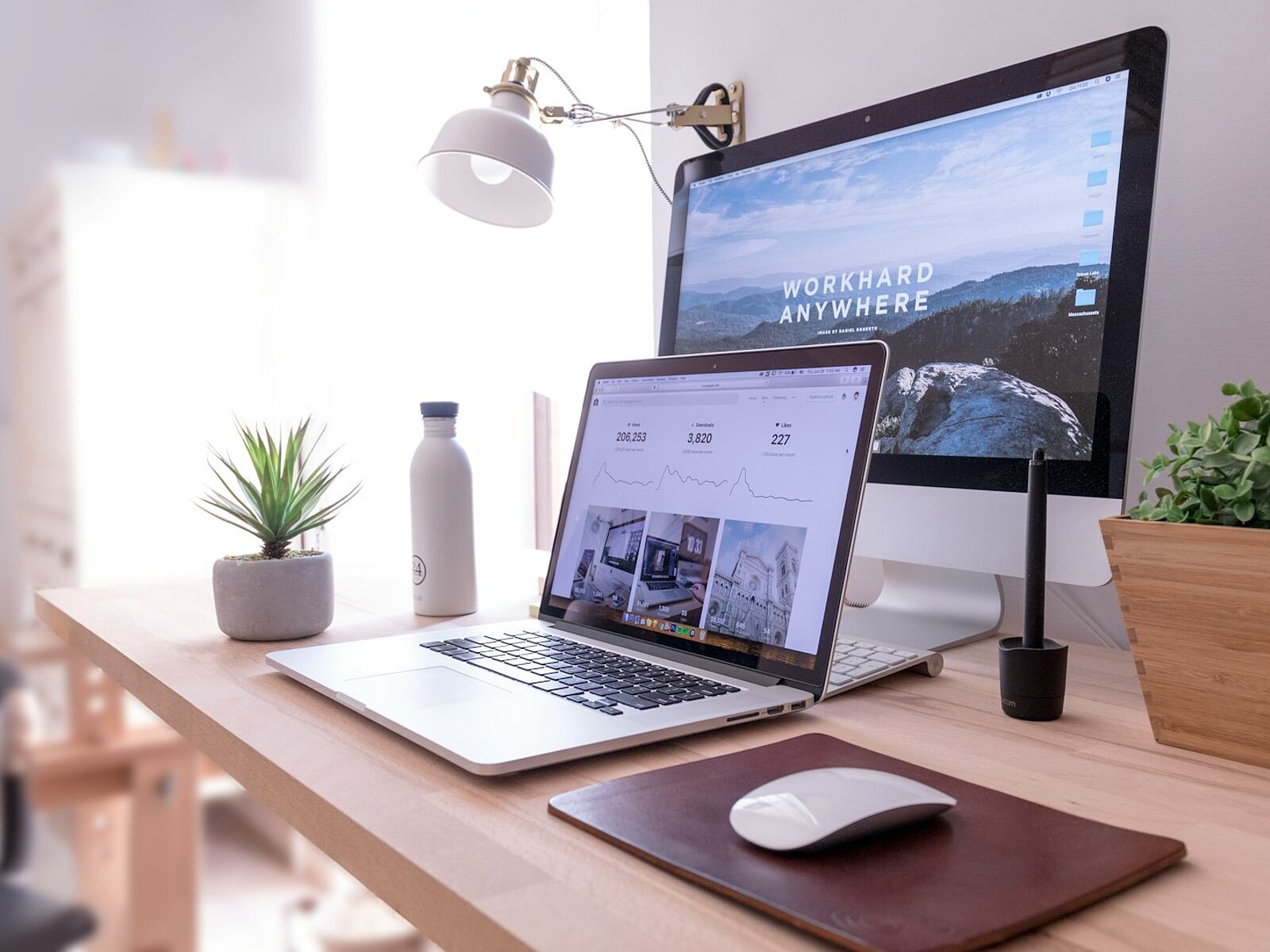 Schreibtisch mit Laptop und Monitor, auf beiden ist eine Website geöffnet